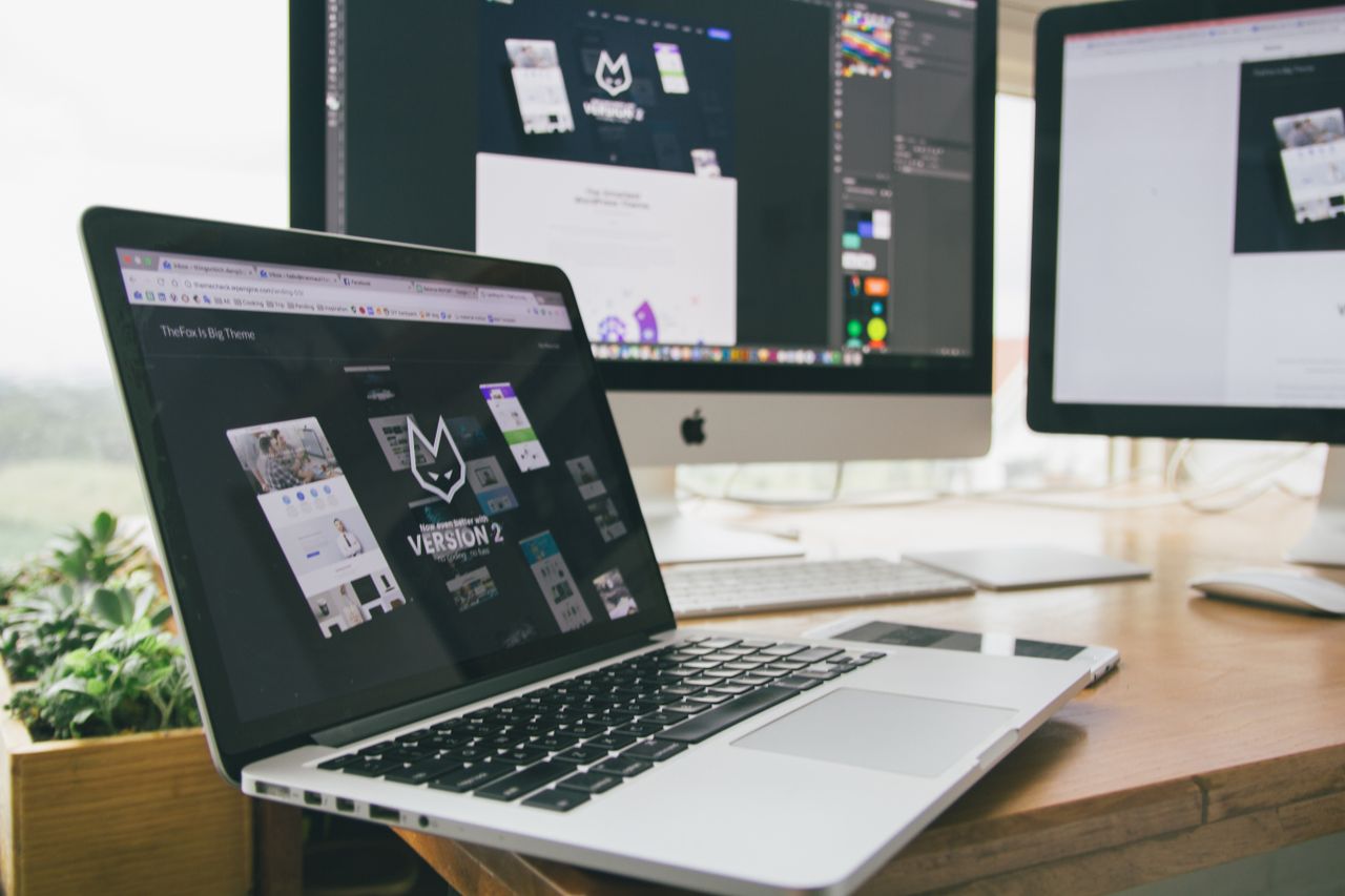 Un espace de travail élégant, avec un ordinateur portable et des écrans affichant un logiciel de conception.